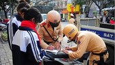 Police officers write ticket to fine two students who violate the traffic law (Photo: SGGP)