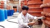 Kiểm tra chất lượng nước mắm trong quá trình rút kéo nước mắm bên trong nhà thùng tại Phú Quốc Ảnh: NGỌC CHÁNH