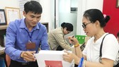 Công chức phường Bến Thành, quận 1, TPHCM đang tiếp nhận, chứng thực hồ sơ sao y của người dân ngoài giờ hành chính. Ảnh: KIỀU PHONG