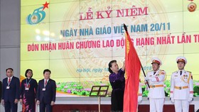 Chủ tịch Quốc hội Nguyễn Thị Kim Ngân gắn Huân chương Lao động hạng Nhất lần thứ hai lên lá cờ truyền thống của Học viện Tài chính. Ảnh: TTXVN