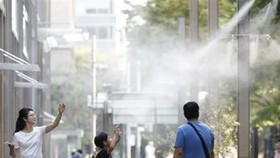 Người dân giải nhiệt tại các vòi phun nước ở Tokyo. (Nguồn: Kyodo/TTXVN)