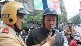 A traffic police officer takes an alcohol test for a motorcyclist. (Photo: VNA)