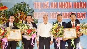 PM Phuc ( white) gives certificates to recognize the two communes to achieve the government's new rural plan (Photo: SGGP)