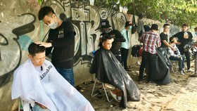 Tiệm cắt tóc miễn phí trên vỉa hè đường Phạm Văn Đồng
