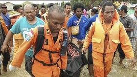 Rescuers carry the body of a flood victim (Photo: VNA)