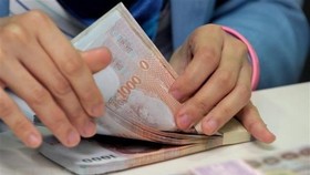 The baht notes are counted at the Krungthai Bank in Bangkok (Illustrative image. Photo: AFP/VNA)