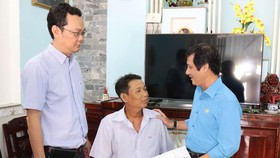 Chủ tịch Công đoàn Sawaco Tô Trung Dũng (bìa phải) và Giám đốc Nhà máy nước Thủ Đức Phạm Tuấn Anh (bìa trái) trao tiền đến anh Nguyễn Anh Tuấn