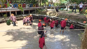 Khách du lịch trải nghiệm việc lội bùn bắt cá