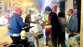 Các tình nguyện viên phân phát cháo cho người lao động và người vô gia cư