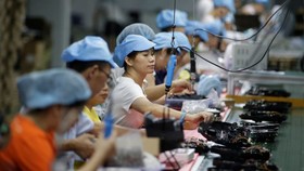 Workers assemble robotic vacuum cleaners at a factory in Shenzhen, China. © Reuters