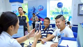 Nhân viên chụp ảnh chân dung khách hàng đến đăng ký thuê bao trả trước mới tại Trung tâm kinh doanh VNPT Vinaphone Hà Nội. (Ảnh: Minh Quyết/TTXVN)