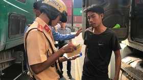 Công an tiến hành kiểm tra tài xế xe container. Ảnh: CHÍ THẠCH