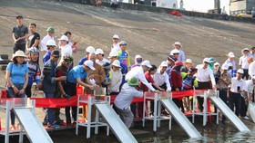 Đại diện các cơ quan chức năng, nhà tài trợ tiến hành thả cá giống xuống lòng hồ thủy điện Sông Tranh 2