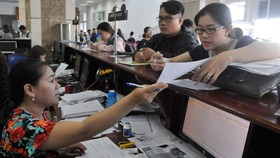Doanh nghiệp nêu thắc mắc với nhân viên Cục Thuế TPHCM. Ảnh: CAO THĂNG