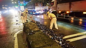 Cảnh sát giao thông hỗ trợ công nhân vệ sinh thu dọn vỏ chai đổ trên đường