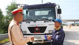 A member of the traffic police checks the paperwork of a truck driver on the Hanoi-Hai Phong Expressway. (Photo: VNA)