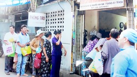 Người nhà bệnh nhân xếp hàng chờ nhận cơm của Bếp ăn từ thiện Bảo Hòa tại Bệnh viện Ung bướu TPHCM