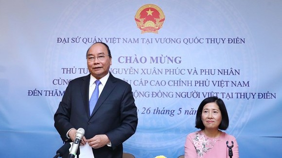 Prime Minister Nguyen Xuan Phuc (standing) speaks at the meeting with the Vietnamese Embassy staff and expatriates in Sweden. (Photo: VNA)