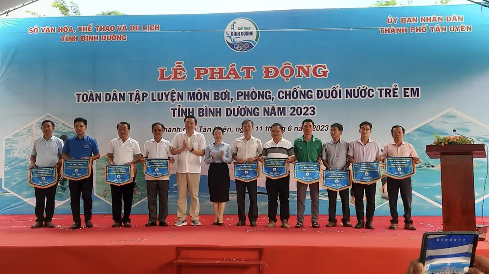 Ông Cao Văn Chóng - PGĐ Sở Văn hóa, Thể thao và Du lịch và bà Nguyễn Thị Kim Nguyên - Phó Chủ tịch UBND thành phố Tân Uyên tặng cờ lưu niệm cho các đơn vị tham dự Lễ Phát động