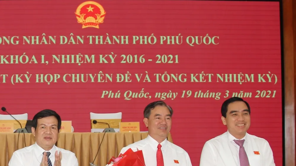 Chủ tịch HĐND TP Phú Quốc Nguyễn Đức Kỉnh (trái) và Chủ tịch UBND TP Phú Quốc Huỳnh Quang Hưng (phải) tặng hoa chúc mừng ông Đoàn Văn Tiến. ẢNH: HOÀNG DUNG