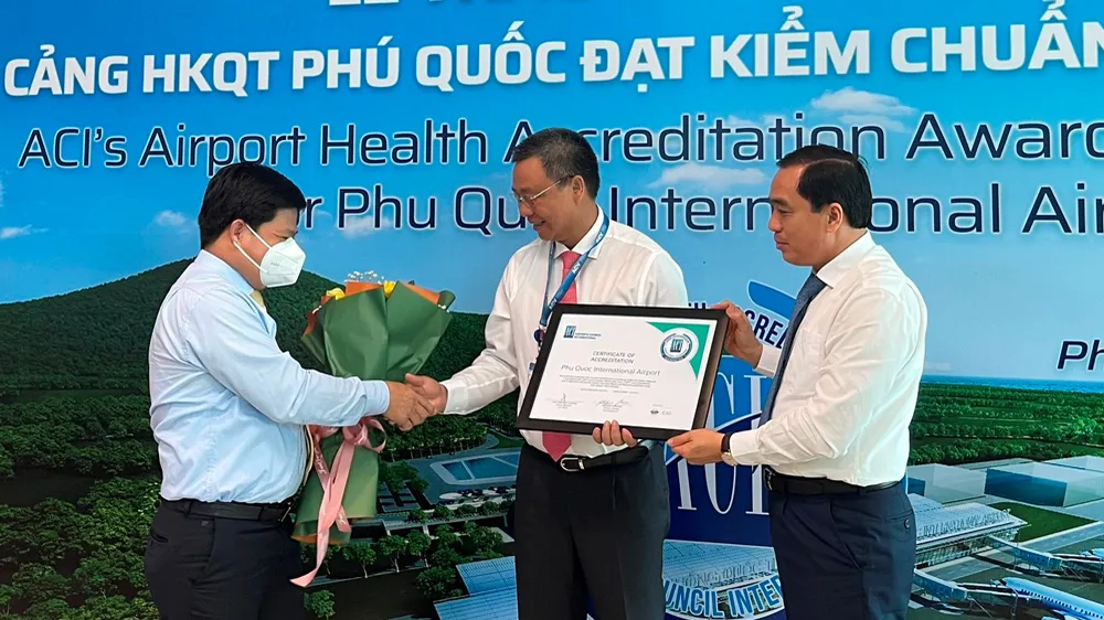 Ông Tống Phước Trường, Bí thư Thành uỷ Phú Quốc (bìa trái) và ông Huỳnh Quang Hưng, Chủ tịch UBND TP Phú Quốc (bìa phải) trao hoa và giấy chứng nhận cho đại diện Cảng HKQT Phú Quốc
