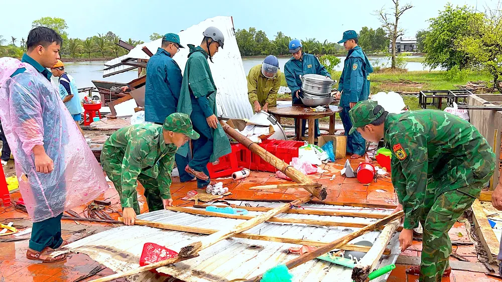 Cán bộ, chiến sĩ Đồn biên phòng Khánh Tiến cùng lực lượng Quân sự xã U Minh hỗ trợ hộ người dân che chắn lại nhà sau thiên tai. ẢNH: HOÀNG TÁ