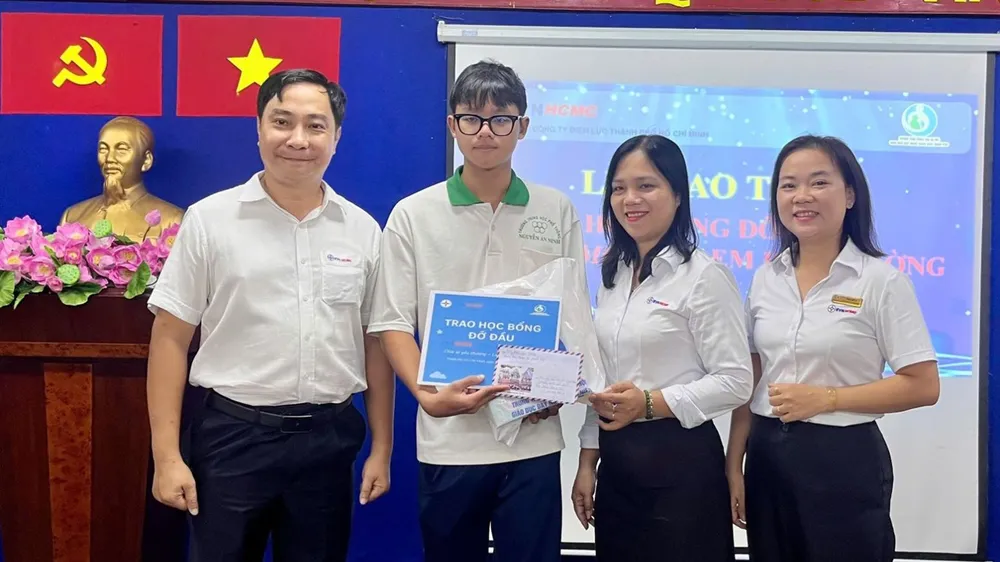 Ông Nguyễn Thanh Nhã, Phó Tổng giám đốc EVNHCMC và đại diện Công đoàn EVNHCMC trao học bổng đỡ đầu cho học sinh tại buổi lễ