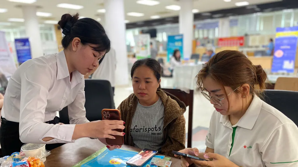 Nhân viên ngân hàng hỗ trợ hộ kinh doanh về công nghệ thông tin (Ảnh: PHÚ NGÂN)