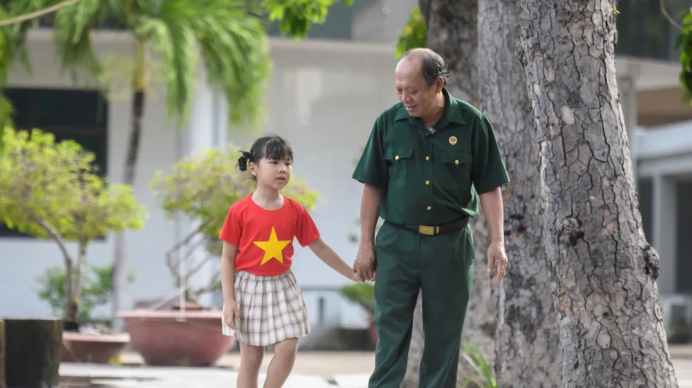 Thượng sĩ Nguyễn Chí Tường cùng con một nhân viên Vinamilk tại Trung tâm Điều dưỡng Thương binh và Người có công Long Đất. Ảnh: THANH BÌNH