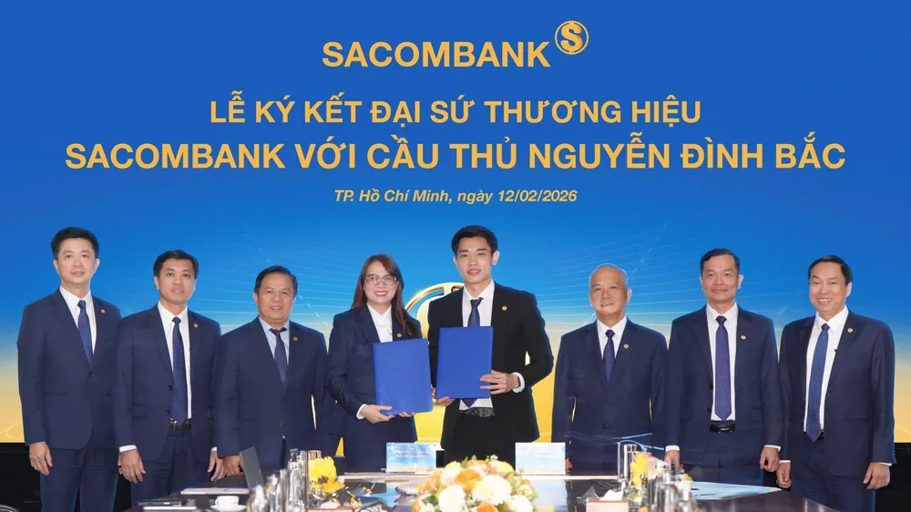 Cầu thủ Nguyễn Đình Bắc (phải) và bà Nguyễn Thị Kiều Anh (trái), Phó Tổng giám đốc SACOMBANK thực hiện nghi thức ký kết Thỏa thuận Đại sứ thương hiệu dưới sự chứng kiến của Ban lãnh đạo Ngân hàng
