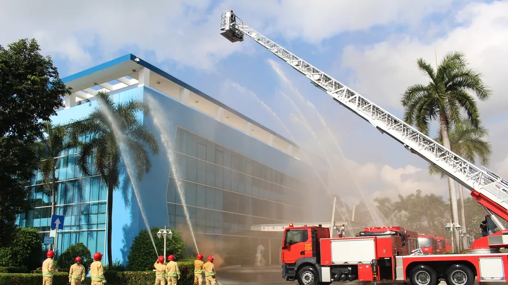 Lực lượng Cảnh sát PCCC-CNCH phối hợp với lực lượng PCCC cơ sở VWS triển khai phương tiện, phun nước từ xe thang trong tình huống diễn tập tại Khu liên hợp Đa Phước.