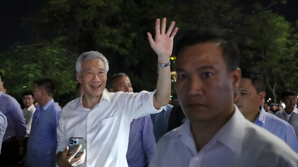Thủ tướng Singapore Lý Hiển Long chào người dân khi dạo phố đi bộ bên hồ Hoàn Kiếm và thăm đền Ngọc Sơn, tối 27-8. Ảnh: QUANG PHÚC