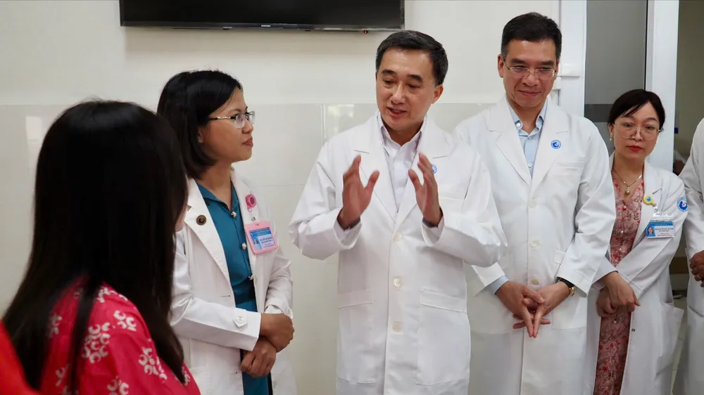 Thứ trưởng Bộ Y tế Trần Văn Thuấn trao tặng hoa và bằng khen cho ekip thực hiện ca can thiệp bào thai cho sản phụ người Singapore Ảnh: HOÀNG HÙNG