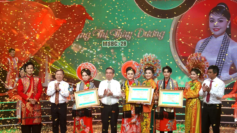 Phó Bí thư Thành ủy, Chủ tịch UBMTTQ Việt Nam TPHCM Nguyễn Phước Lộc, Trưởng Ban Tuyên giáo và Dân vận Thành ủy TPHCM Dương Anh Đức và Tổng Giám đốc Đài Truyền hình TPHCM Cao Anh Minh, trao giải thưởng Chuông Vàng cho thí sinh Đặng Thị Thùy Dương và cùng chụp hình với các nghệ sĩ trong ban huấn luyện. Ảnh: THÚY BÌNH