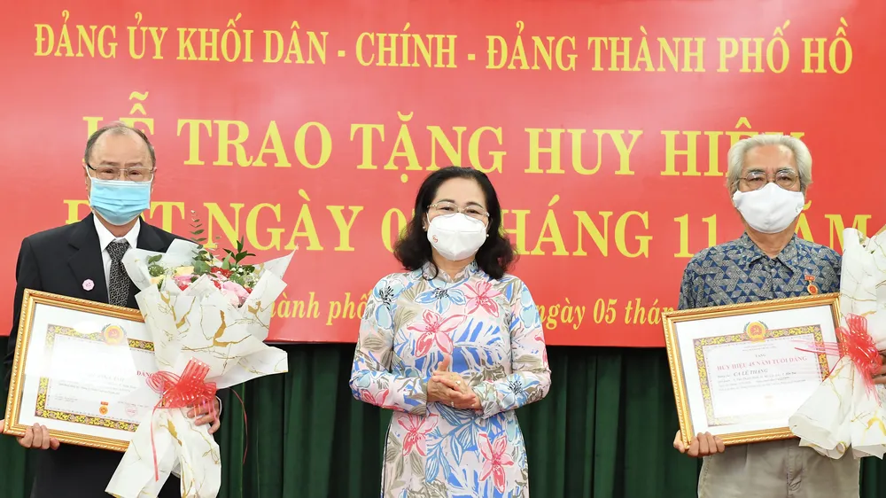 Chủ tịch HĐND TPHCM Nguyễn Thị Lệ trao Huy hiệu 45 năm tuổi Đảng cho đồng chí Ca Lê Thắng và đồng chí Bùi Quang Cảnh. Ảnh: VIỆT DŨNG