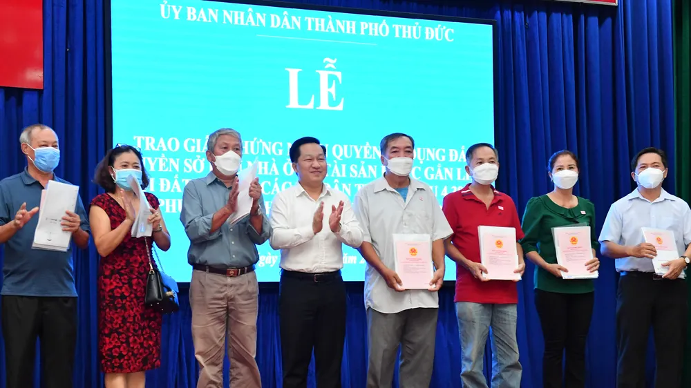 Chủ tịch UBND TP Thủ Đức Hoàng Tùng trao giấy chứng nhận quyền sử dụng đất, quyền sở hữu nhà ở và tài sản khác gắn liền với đất cho các hộ dân. Ảnh: VIỆT DŨNG