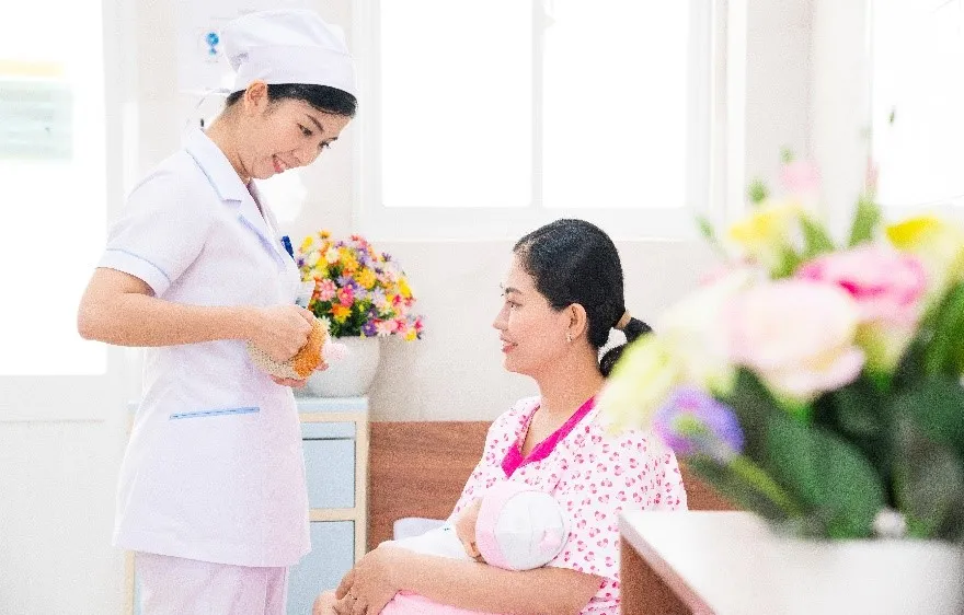 Nữ hộ sinh tư vấn cho sản phụ về tư thế cho con bú.