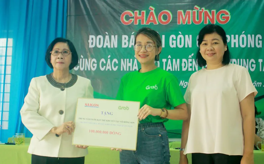 Bà Lý Việt Trung, Phó Tổng Biên tập Báo SGGP (bên phải) cùng đại diện Công ty TNHH Grab trao hỗ trợ 100 triệu đồng cho bà Nguyễn Thị Thu Hà, Giám đốc Trung tâm Võ Hồng Sơn. Ảnh: NGUYỄN TRANG