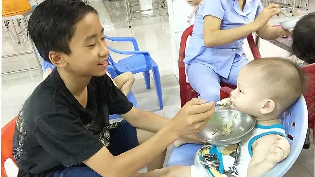 Không chỉ học giỏi, Trần Văn Minh còn biết phụ giúp các cô tại trung tâm chăm sóc các em nhỏ.