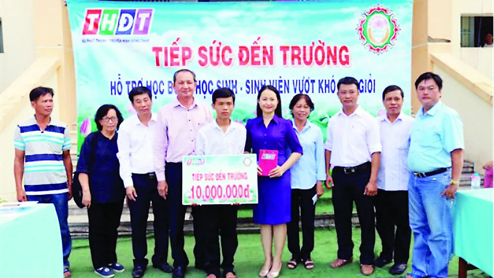 Ông Lưu Hoàng Tân - Chủ tịch, Giám đốc Công ty TNHH MTV Xổ số kiến thiết tỉnh Đồng Tháp (thứ 7 từ phải sang) trao học bổng cho em Vinh
