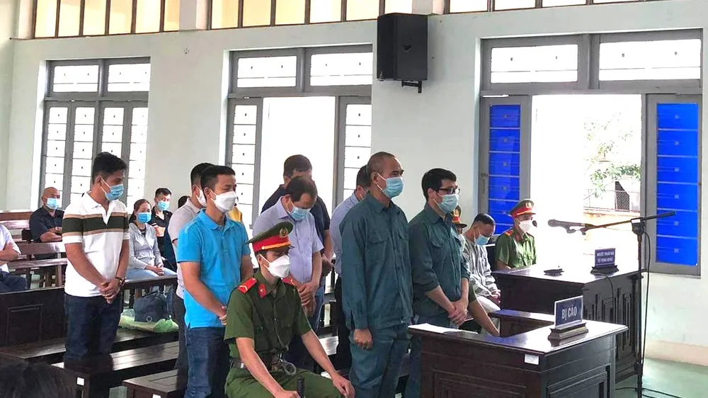 Luyện Xuân Tràng (người đeo kính) cùng 8 bị cáo khác tại phiên tòa. ​