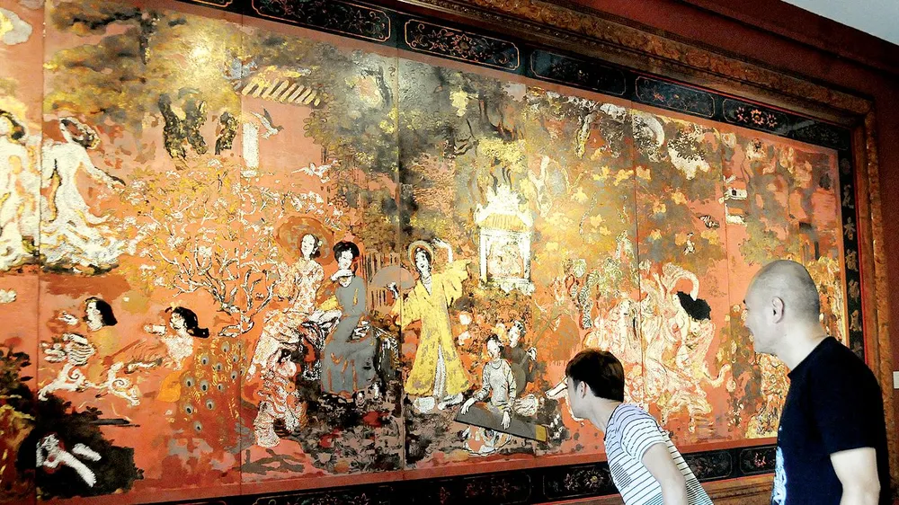 Khách tham quan xem tác phẩm sơn mài Vườn xuân Trung - Nam - Bắc của danh họa Nguyễn Gia Trí. Ảnh: AN DUNG