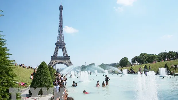 Người dân tránh nắng nóng bên vòi phun nước ở Paris, Pháp. Ảnh: TTXVN