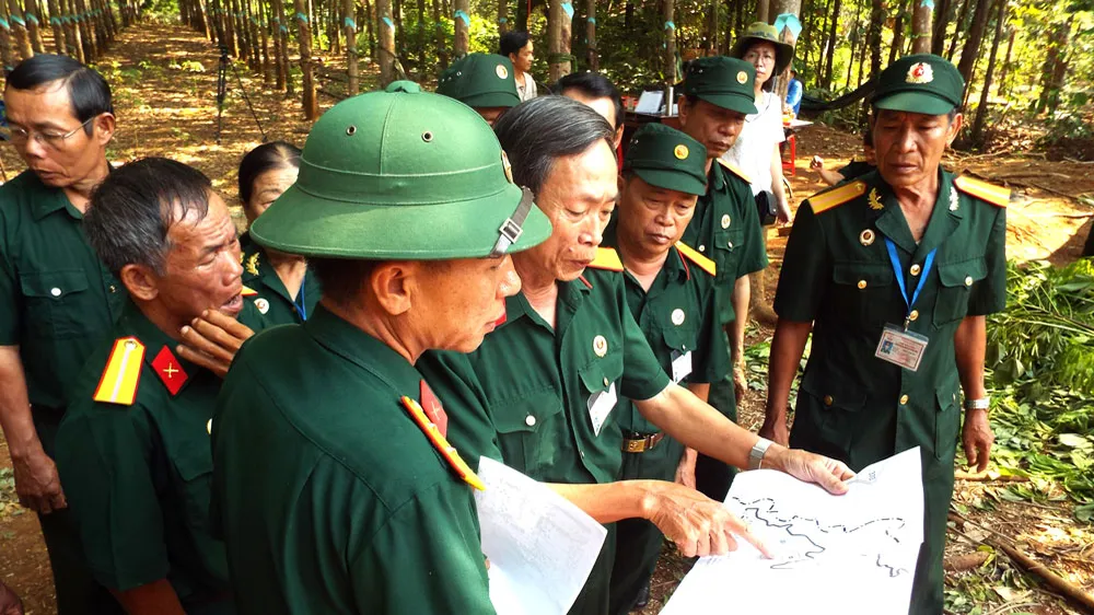 Thương binh Vũ Đình Luật (người chỉ tay vào bản đồ) trong lần đi tìm hài cốt đồng đội 