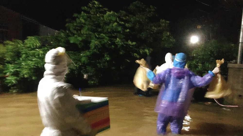 Đội phản ứng nhanh huyện Phong Điền lội lũ đi lấy mẫu xét nghiệm Covid-19 trong đêm 11-9. ​
