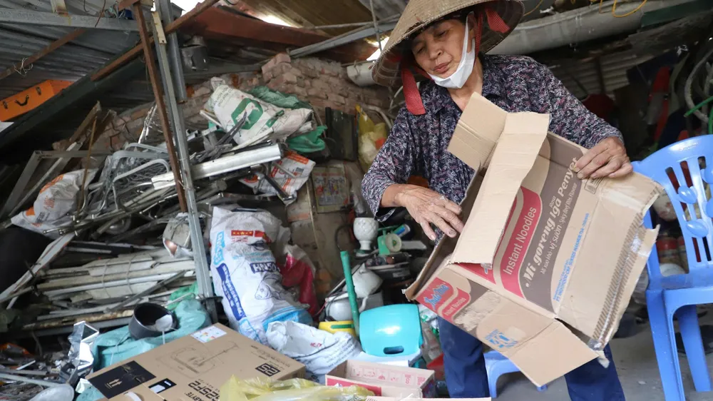 Bà Nguyễn Thị Hoa đang nhặt phế liệu tại căn nhà vừa tháo dỡ. Ảnh: TIẾN CƯỜNG