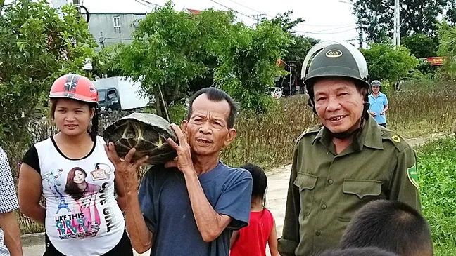 Ông Thể và đại diện chính quyền địa phương cùng người dân mang con rùa đi thả về lại môi trường tự nhiên