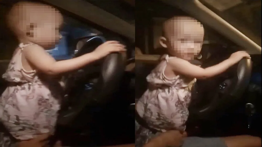 Cháu bé với hai tay đang cầm vô lăng xe ô tô. Ảnh cắt từ clip