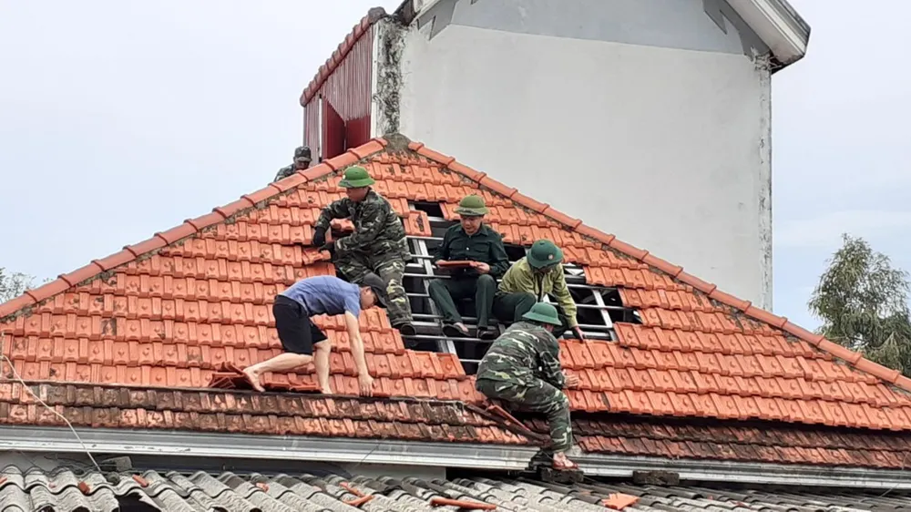 Lực lượng chức năng giúp người dân xã Thịnh Lộc, huyện Lộc Hà lợp lại mái nhà sau thiệt hại do lốc xoáy gây ra