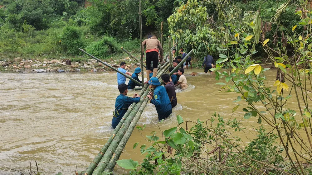 Các lực lượng chức năng và người dân xã Yên Na làm cầu tạm qua khe Chà Hạ vào hai bản cô lập 